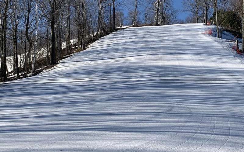 Freshly groomed corduroy slope at Willard Mountain under a clear blue sky